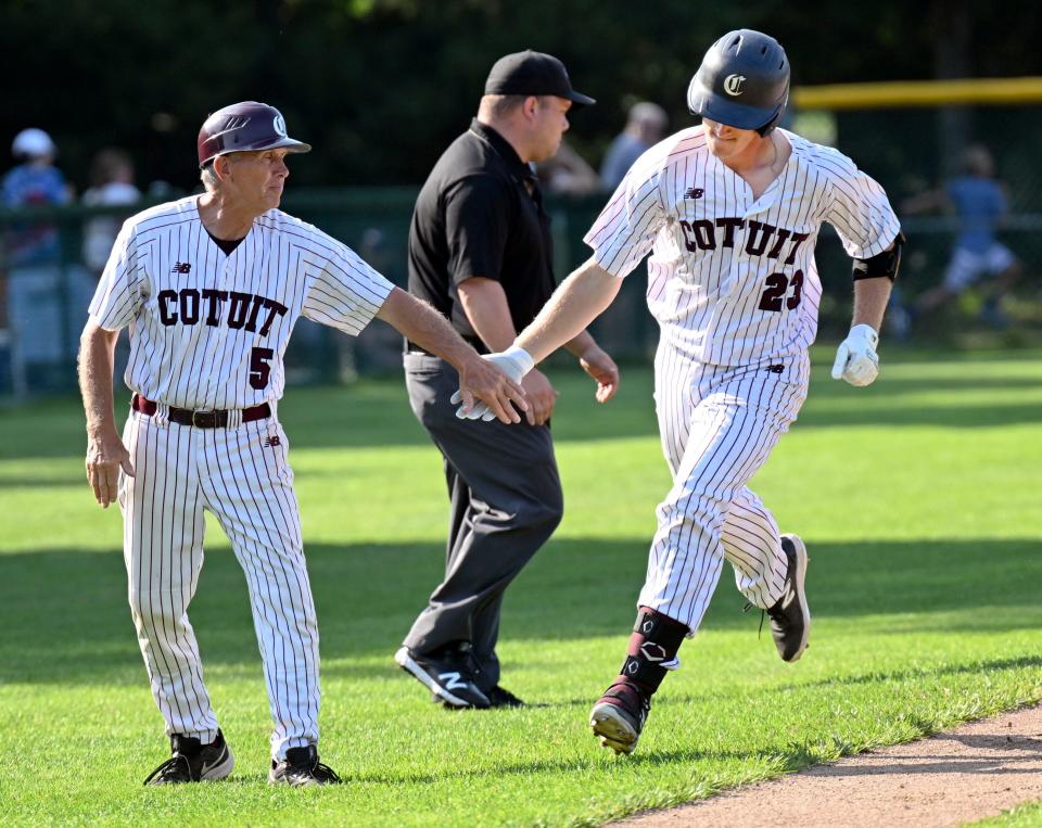 Cole Mathis is welcomed by Cotuit field manager Mike Roberts as he rounds third on a home run against Falmouth on Wednesday.