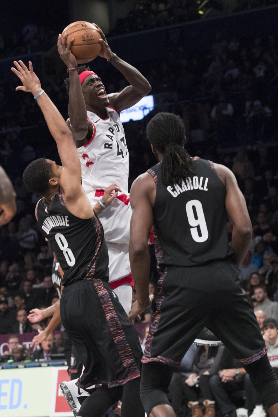Toronto Raptors forward Pascal Siakam (43) goes to the basket against Brooklyn Nets guard Spencer Dinwiddie (8) and forward DeMarre Carroll (9) during the first half of an NBA basketball game, Friday, Dec. 7, 2018, in New York. (AP Photo/Mary Altaffer)