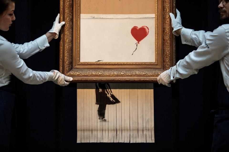 Sotheby's employees pose with 'Love is in the Bin' by British artist Banksy during a media preview at Sotheby's auction house (Jack Taylor/Getty Images)