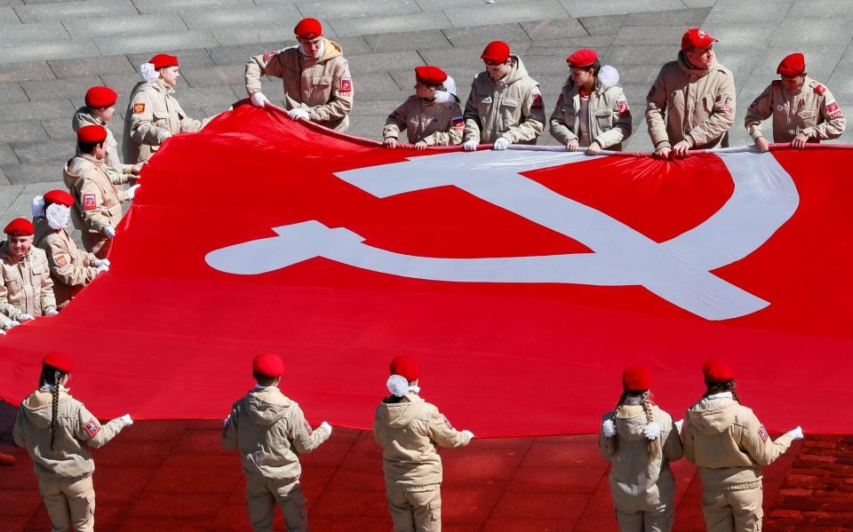 Russians hold a giant replica of the victory banner as they attend an event commemorating victory in WWII near the Museum of the Great Patriotic War in Moscow