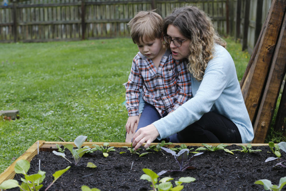 Stephanie Owens looks over the garden with her son, Cole, as they tend to it at their home Wednesday March 25 , 2020, in Glen Allen, Va. Owens is a pharmacist who has had to continue to go to work, but has been able to spend more time with her kids because they are home from school . One of the activities that they have done is planting the garden. (AP Photo/Steve Helber)