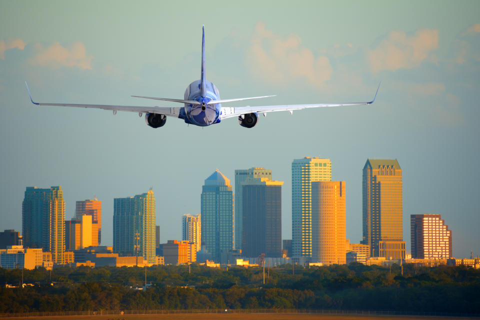 Tampa, Florida, skyline with warm sunset light with a commercial passenger jet airliner plane arriving or departing the International Airport.