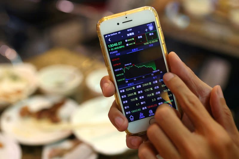 FILE PHOTO: A person displays stock data on his phone in a restaurant in Taipei,