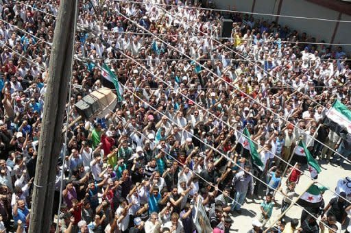 A handout image released by the Syrian opposition's Shaam News Network shows people chanting and holding up the adopted Syrian revolutionary flag during the funeral of Abdelkader Tahina in the Syrian town of Dael