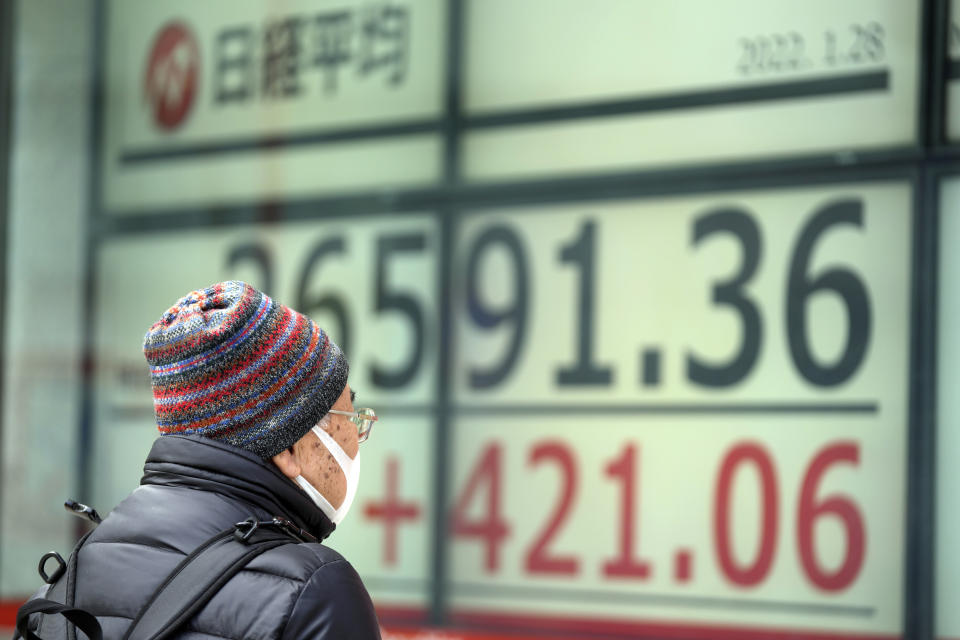 A man wearing a protective mask looks at an electronic stock board showing Japan's Nikkei 225 index at a securities firm Friday, Jan. 28, 2022, in Tokyo. Asian stock markets were mixed Friday as traders looked ahead to data on U.S. employment costs that might influence Federal Reserve decisions on planned interest rate hikes. (AP Photo/Eugene Hoshiko)