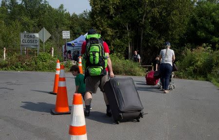 A Syrian family follows the cones to cross the U.S.-Canada border into Canada from Champlain, New York, U.S., August 3, 2017. REUTERS/Christinne Muschi