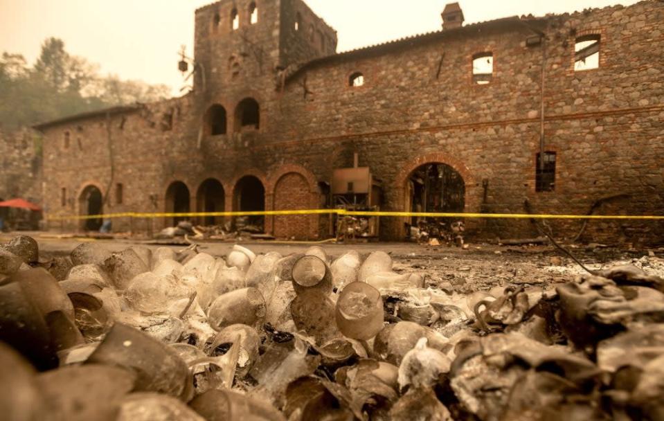 A pile of melted wine glasses sit in front of the burned remains of the Castello Di Amorosa winery following a wildfire in Calistoga, California (AFP via Getty)