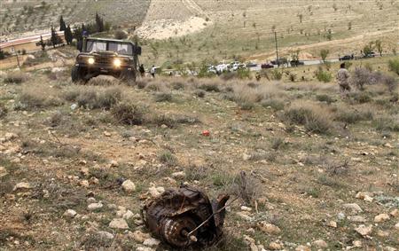 A Lebanese army vehicle is seen near the remains of a car which was blown up by the army after they suspected that it contained explosives, in east Bekaa March 17, 2014. REUTERS/Ahmad Shalha