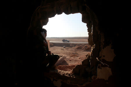 Policemen look through a hole in a house from the clashes in Qaraqosh, near Mosul, Iraq, December 9, 2016. REUTERS/Alaa Al-Marjani