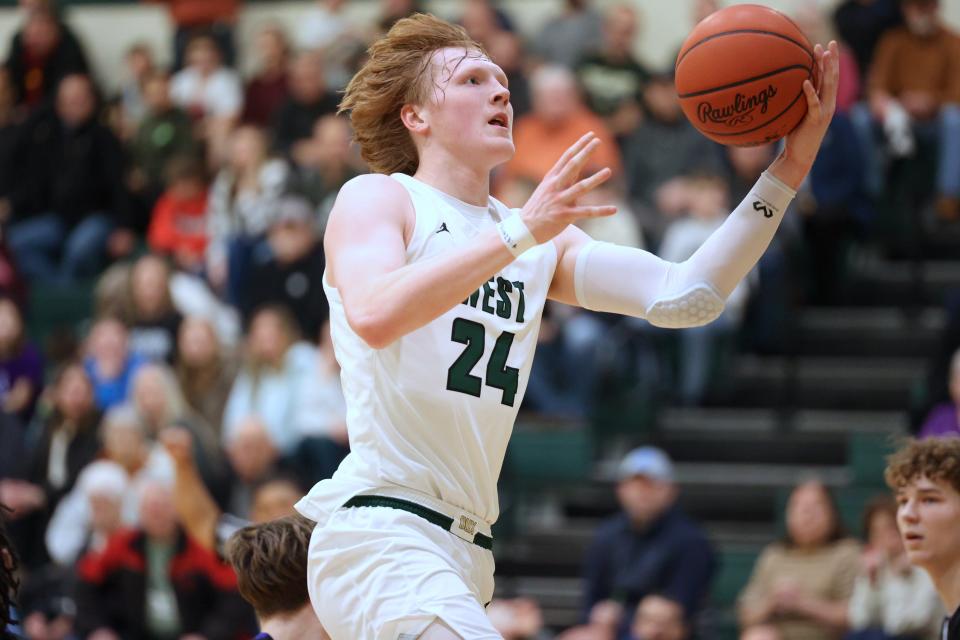 The Zeeland West boys basketball team celebrates a win over Wyoming and Merritt Alderink's 1,000 career point on Friday.