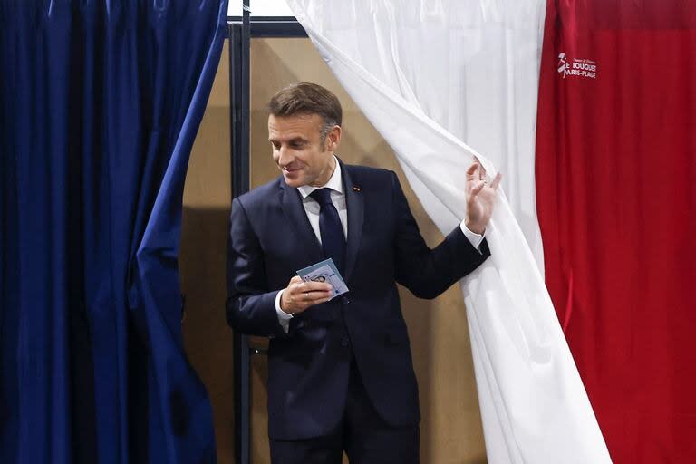 El presidente de Francia, Emmanuel Macron, sale de una cabina electoral, adornada con cortinas que muestran los colores de la bandera de Francia, para votar en la segunda vuelta de las elecciones legislativas de Francia en un colegio electoral en Le Touquet, al norte de Francia, el 7 de julio de 2024. Francia votos en las elecciones legislativas del 7 de julio de 2024