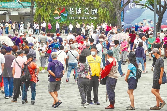 台北市花博公園大型接種站14日仍湧入大批民眾，排隊長龍蜿蜒約1公里，13日因現場混亂引發民怨，市政府昨派出大批工作人員疏導，秩序大致良好。（黃子明攝）