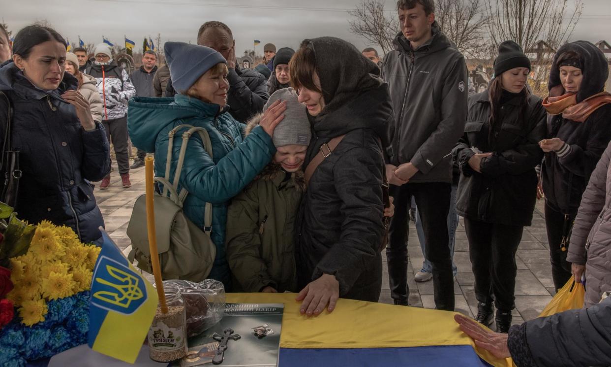 <span>Lilia (centre right) and nine-year-old Matviy (centre), the wife and son of Andriy Katanenko, 39, who was killed in action near Avdiivka, mourn next to his coffin during a funeral ceremony in Bucha, north-west of Kyiv.</span><span>Photograph: Roman Pilipey/AFP/Getty Images</span>