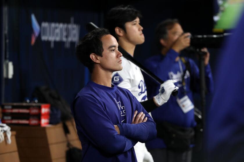 Will Ireton folds his arms while standing next to Shohei Ohtani in the Dodgers dugout