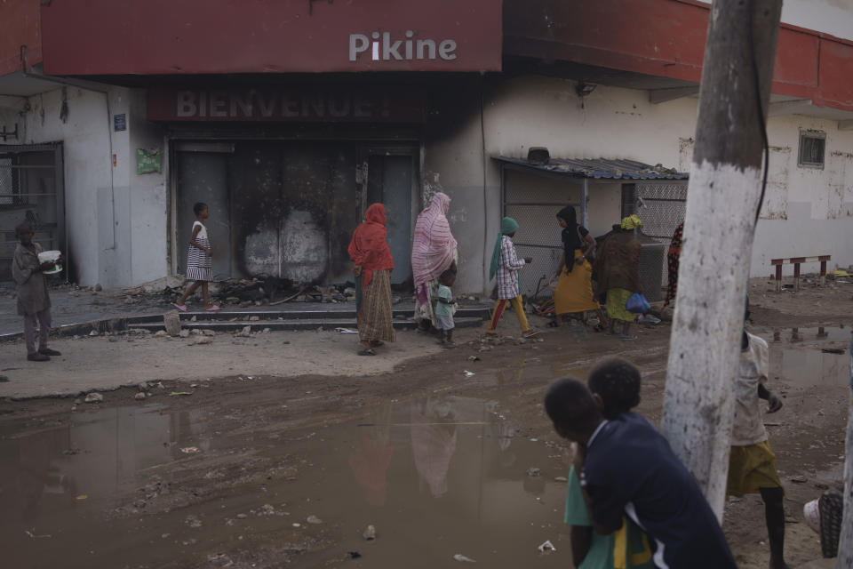 People walk past a supermarket that was damaged during protests yesterday in Pikine, Dakar region, Senegal, Tuesday, May 16, 2023. According to the authorities at least three people died, including a police officer who was hit by a police vehicle, in Dakar and Ziguinchor during clashes between security forces and supporters of Senegalese opposition leader Ousmane Sonko. (AP Photo/Leo Correa)