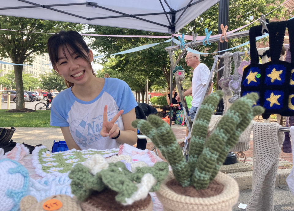 Emily Chen poses Wednesday next to her crocheted succulents, bags, and coasters