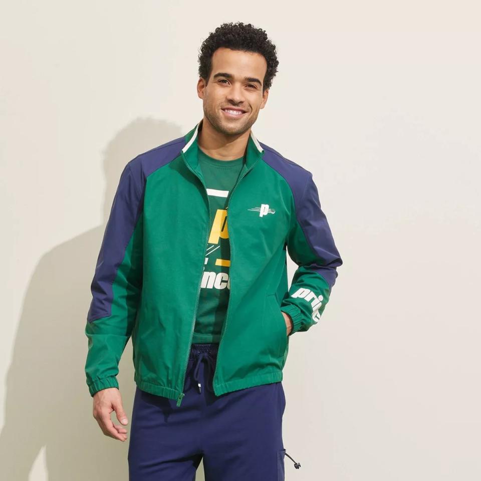 model wearing green and navy blue zip-up jacket with blue sweatpants