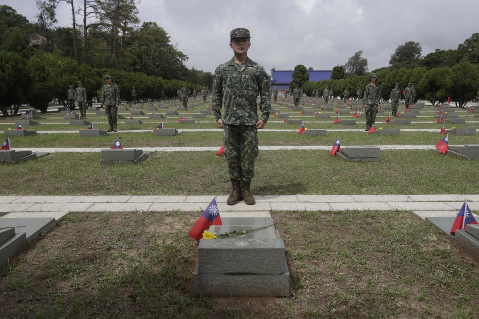 Soldiers stand at the gravestones to salute the fallen during a ceremony commemorating the 65th anniversary of deadly attack by China on Kinmen island, in Kinmen, Taiwan, Wednesday, Aug. 23, 2023. (AP Photo/Chiang Ying-ying)