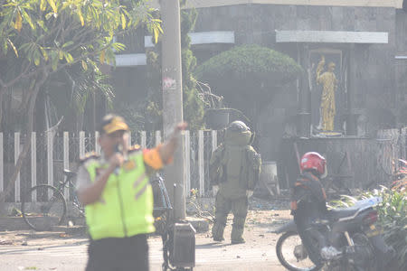 A member of the police bomb squad unit examines the site of an explosion outside the Immaculate Santa Maria Catholic Church, in Surabaya, East Java, Indonesia May 13, 2018 in this photo taken by Antara Foto. Antara Foto/M Risyal Hidayat / via REUTERS
