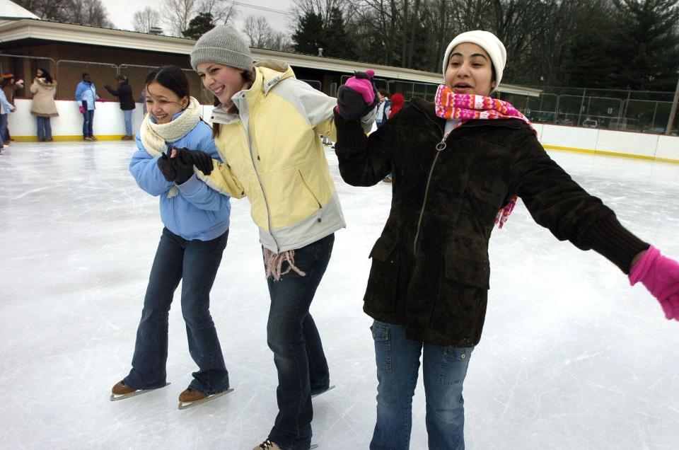 Tehmina Bromand, 14, left, and Storay Siddiqi, 19, right, are held up by Martha Pettijohn, center, while ice skating.