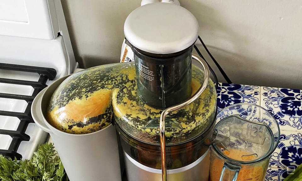 The Breville juice fountain plus sits on a countertop. It has just been used to make an orange drink from carrots and oranges. Lots of pulp covers the inner dome of the juicer. 