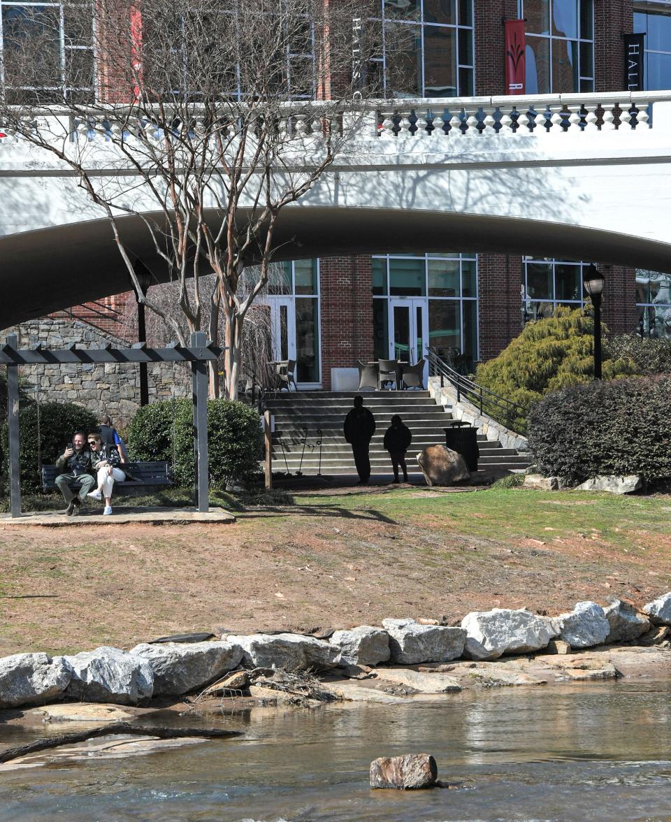 People visit the walking paths, park benches, and bridge over Falls Park near Halls Steakhouse in downtown Greenville, S.C.