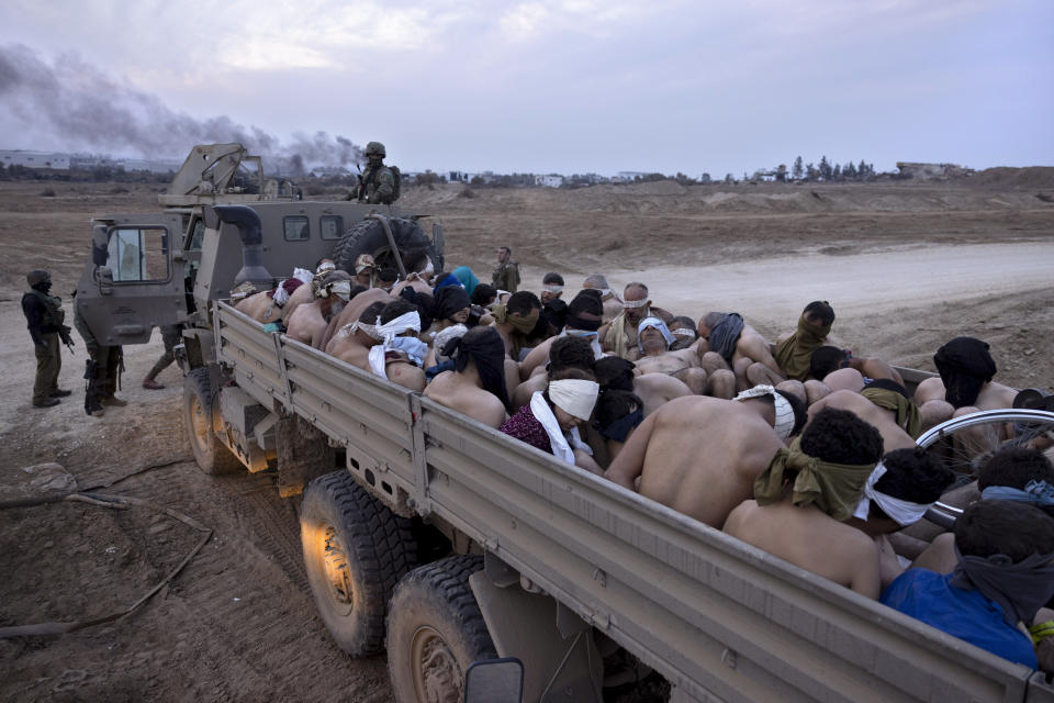 FILE - Israeli soldiers stand by a truck packed with bound and blindfolded Palestinian detainees, in Gaza, Friday, Dec. 8, 2023. (AP Photo/Moti Milrod, Haaretz, File)