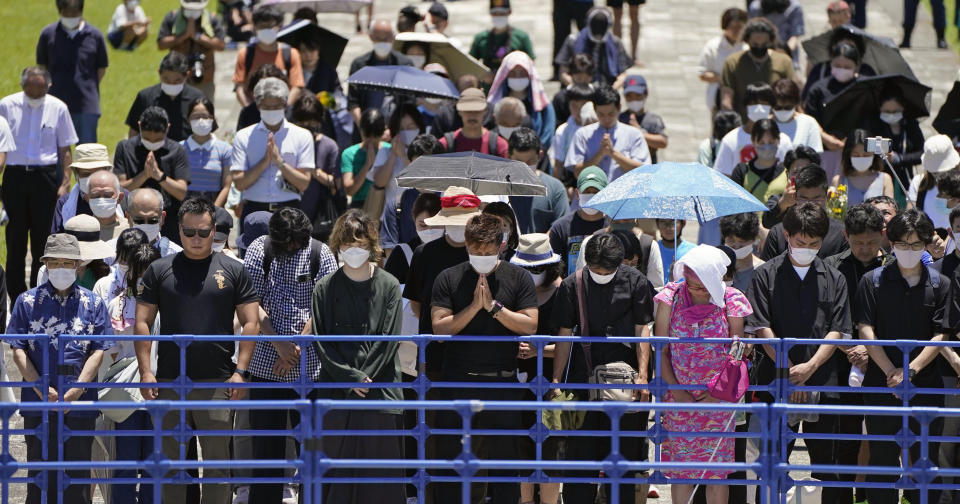 People offer a silent prayer around a venue for a memorial ceremony in Itoman, Okinawa, southern Japan Thursday, June 23, 2022. Japan marked the Battle of Okinawa, one of the bloodiest battles of World War II fought on the southern Japanese island, which ended 77 years ago, Thursday. (Kyodo News via AP)