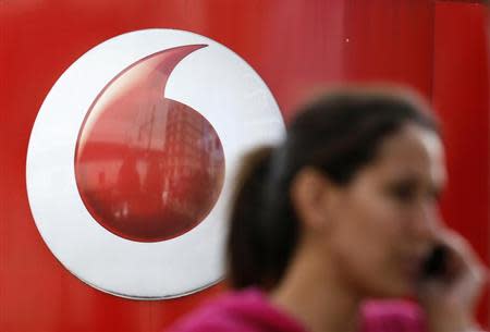 A woman talks on her mobile phone as she walks past a Vodafone store in London September 2, 2013. REUTERS/Stefan Wermuth