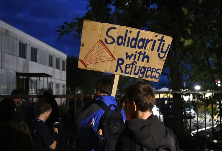 Protester holds a banner reading "Solidarity with Refugees" in front of a German Red Cross camp for refugees following a pro-Asylum demo in Dresden, eastern Germany, on July 28, 2015