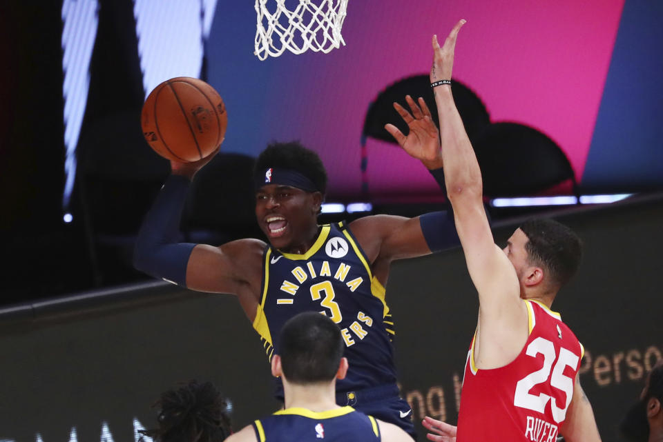 Indiana Pacers guard Aaron Holiday, center, passes the ball away from Houston Rockets guard Austin Rivers, right, in the first half of an NBA basketball game Wednesday, Aug. 12, 2020, in Lake Buena Vista, Fla. (Kim Klement/Pool Photo via AP)