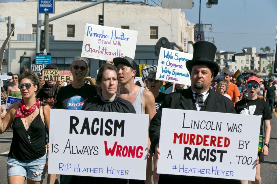 Mike Stutz, right, dressed as President Abraham Lincoln, and Laurel Trotter, next to him, dressed as Mary Todd Lincoln, join marchers in downtown Los Angeles on Sunday, Aug. 13, 2017. Protesters decrying hatred and racism converged around the country Sunday, the day after a white supremacist rally that spiraled into violence in Charlottesville, Va.  (AP Photo/Damian Dovarganes)