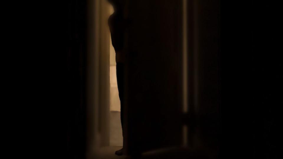 silhouette of person peeking into dark room through a cracked door