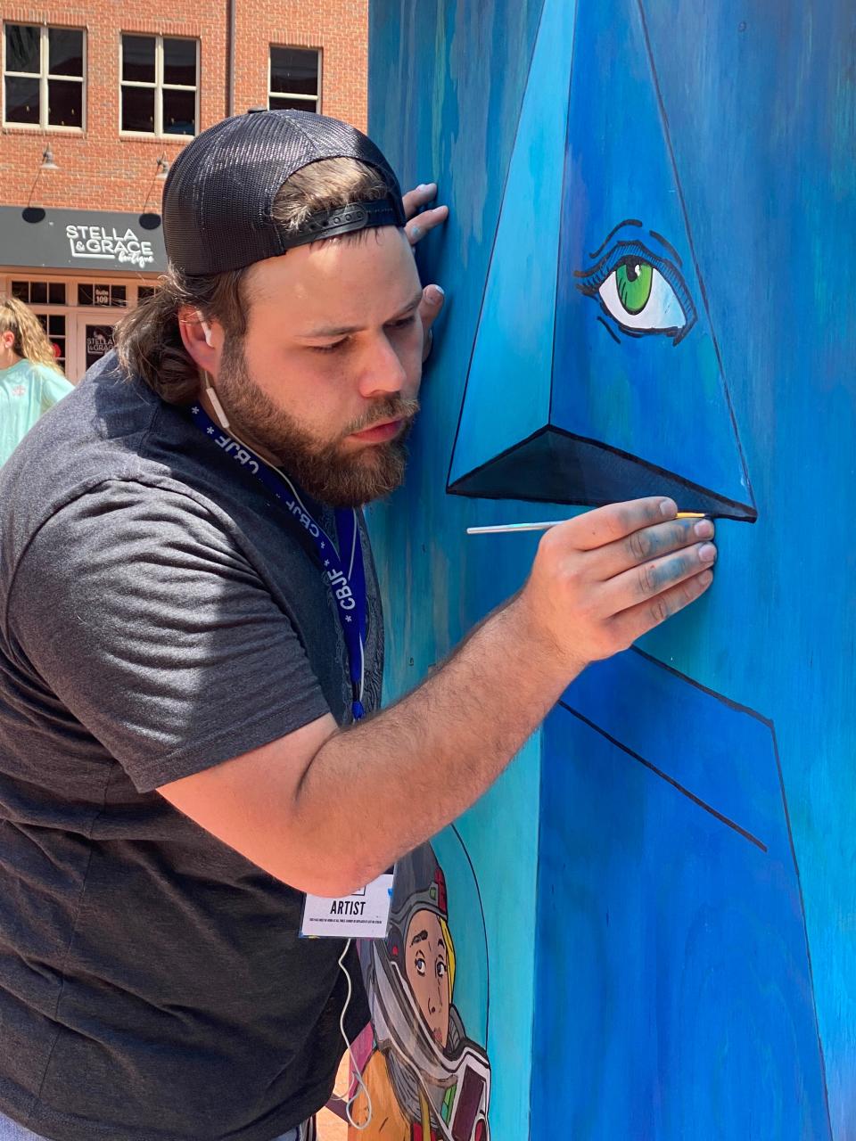 Columbus artist Joseph Dulin-Didonato works on a mini mural on Creekside Plaza that includes a reinterpretation of his daughter in the lower left corner. He said a comic book artist is one of his inspirations.
