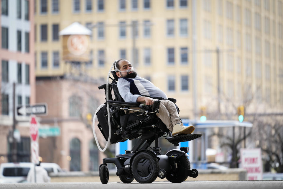 Temple University doctoral student Jaggar DeMarco poses for a portrait while utilizing a battery powered ventilator in Philadelphia, Wednesday, March 6, 2024. These “noninvasive” ventilators help patients breathe around the clock by forcing air into the lungs, often through a mask. They are called noninvasive because they don’t require trachea surgery to open the airway, like ones used in hospitals. (AP Photo/Matt Rourke)