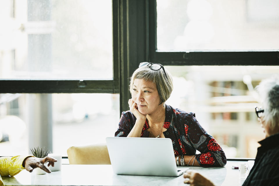 Mature businesswoman listening during meeting with clients in office