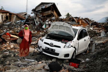 Juliana Lasarudin, 48, stands next to her car in front of her destroyed house after it was hit by an earthquake, in Balaroa neighbourhood in Palu, Central Sulawesi, Indonesia, October 9, 2018. REUTERS/Jorge Silva