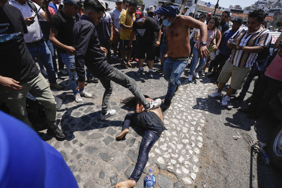 Una turba golpea brutalmente a una mujer, que murió después, al ser señalada como sospechosa del secuestro y asesinato de una niña de 9 años, después de sacarla de un vehículo policial, en Taxco, México, el jueves 28 de marzo de 2024 (AP Foto/Fernando Llano)