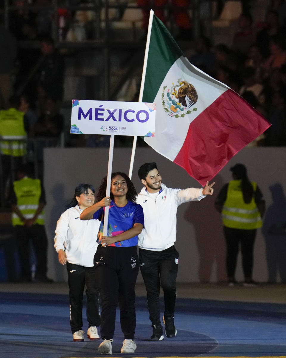 La gimnasta Alexa Moreno y el pesista Jorge Cárdenas portan la bandera de México durante la ceremonia inaugural de los Juegos Centroamericanos y del Caribe, el viernes 23 de junio de 2023, en San Salvador (AP Foto/Arnulfo Franco)