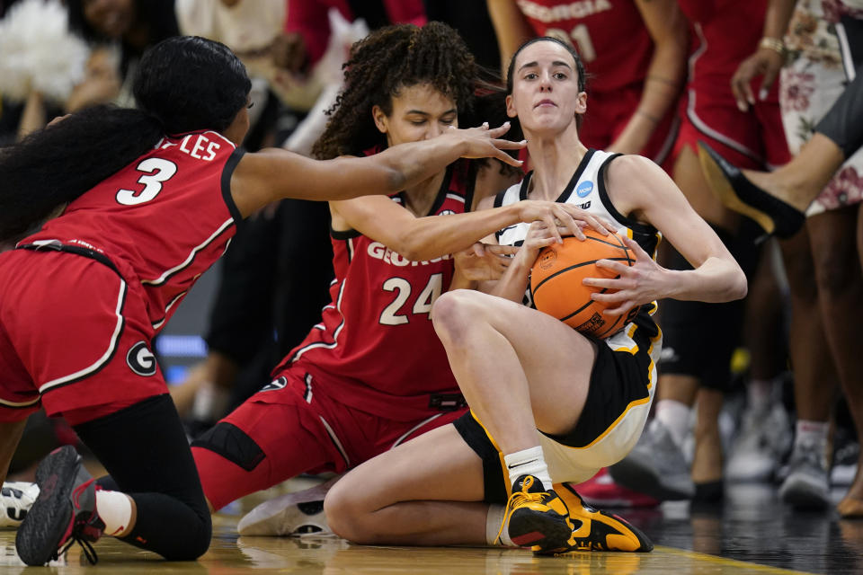 Iowa guard Caitlin Clark, right, fights for a loose ball with Georgia guard Diamond Battles, left, and forward Brittney Smith, center, in the first half of a second-round college basketball game in the NCAA Tournament, Sunday, March 19, 2023, in Iowa City, Iowa. (AP Photo/Charlie Neibergall)