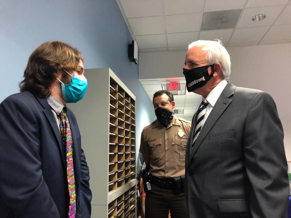 Miami teacher Benjamin Torrens, left, talks with Miami-Dade Mayor Carlos Gimenez after receiving a certificate of appreciation for his role in helping defend a Miami CVS from people trying to damage it after protests Sunday night against racism by police. Looking on is Freddy Ramirez, the county’s police director, who presented Torrens with one of the agency’s commemorative coins.