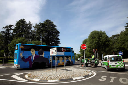 A municipal worker points at a bus sponsored by Podemos (We can) party painted with pictures representing Spain's recent political scandals as it tours Madrid, Spain April 18, 2017. Picture taken April 18, 2017. REUTERS/Susana Vera