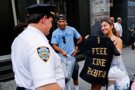 A shopper shows her "The Life of Pablo" merchandise to NYPD officers after visiting a pop up store featuring fashion by Kanye West in Manhattan, New York, U.S., August 19, 2016. REUTERS/Eduardo Munoz