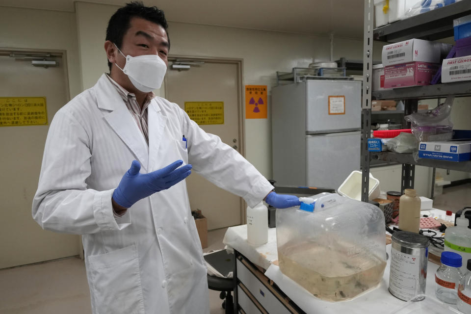 University of Tokyo radiologist Katsumi Shozugawa shows a container which holds contaminated water, at his university laboratory in Tokyo on Feb. 16, 2023. Shozugawa said his analysis of groundwater in multiple locations in no-go zones near the plant has shown that tritium and other radioactive elements have been leaking into groundwater. (AP Photo/Shuji Kajiyama)