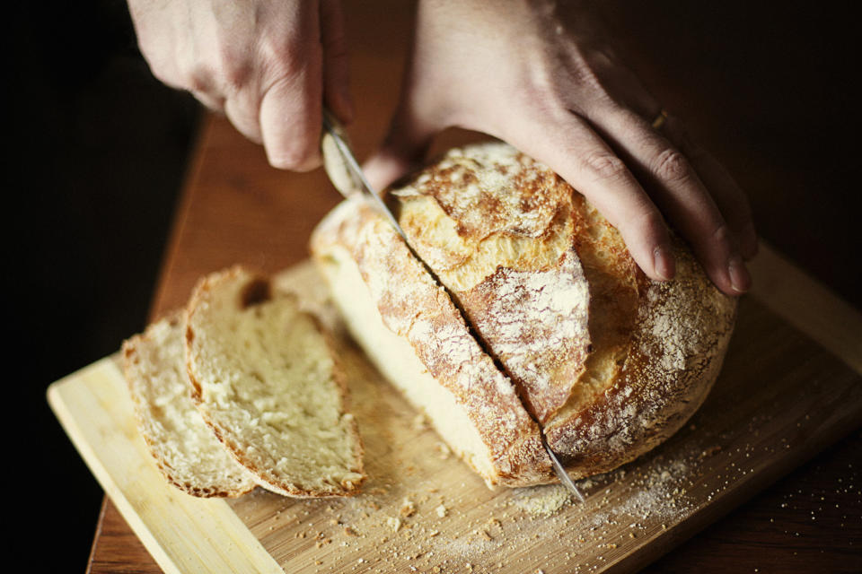 someone cutting a slice of bread