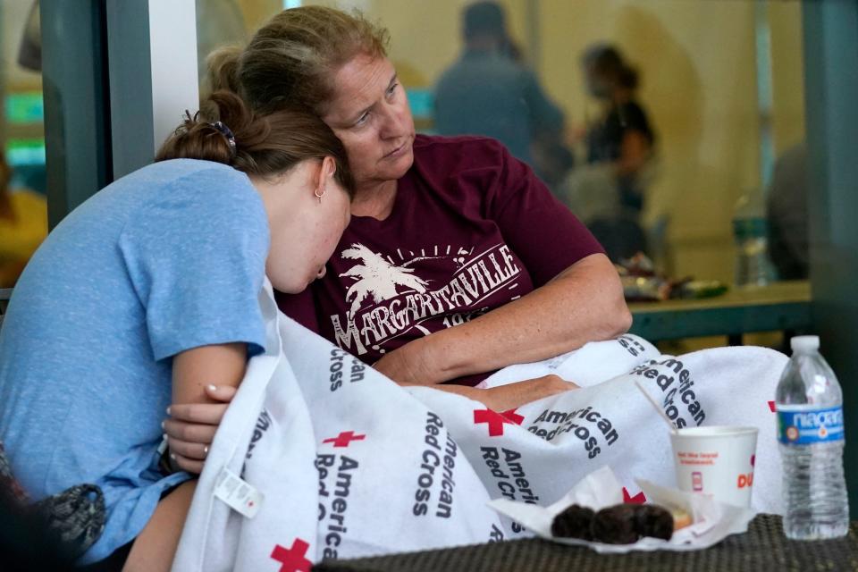 Jennifer Carr, right, sits with her daughter as they wait for news at a family reunification center.