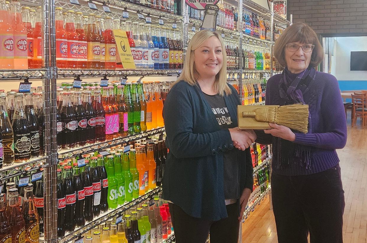 Manager Emily Lovett accepts the Golden Broom Award from Grandpa Joe's Candy Shop from Nancy Ames.