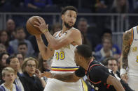 Golden State Warriors guard Stephen Curry (30) looks to pass over Toronto Raptors guard Norman Powell during the first half of an NBA basketball game in San Francisco, Thursday, March 5, 2020. (AP Photo/Jeff Chiu)