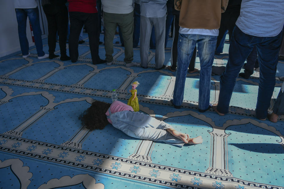A girl lies on the floor as men pray in a mosque in Athens, Greece, Friday, Oct. 13, 2023. In Muslim communities across the world, worshippers gathered at mosques for their first Friday prayers since Hamas militants attacked Israel, igniting the latest Israel-Hamas war. (AP Photo/Michael Varaklas)