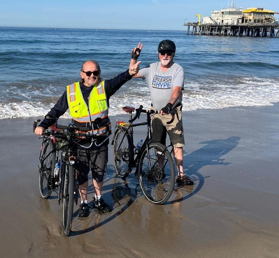 Dipping tires in the Pacific Ocean. Thomas "Tommy" Taylor, left, and John "J.D." Norton have embarked on a bike trip that will take them from Santa Monica to Boston, with a special stop Tuesday in Barstow.